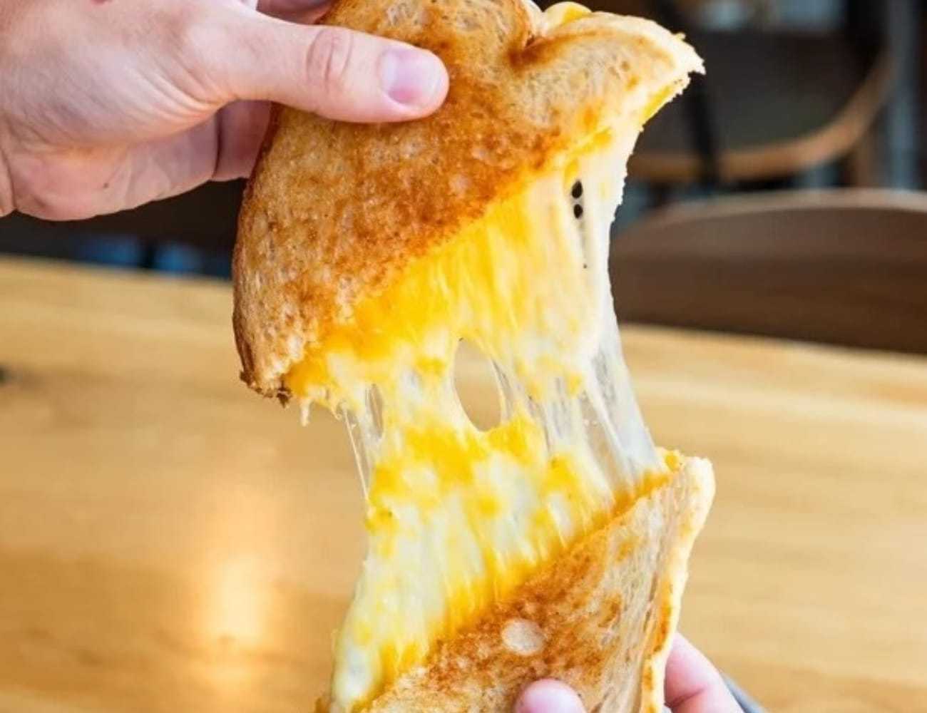 Grilled cheese sandwich being pulled apart, showing gooey melted cheese.
