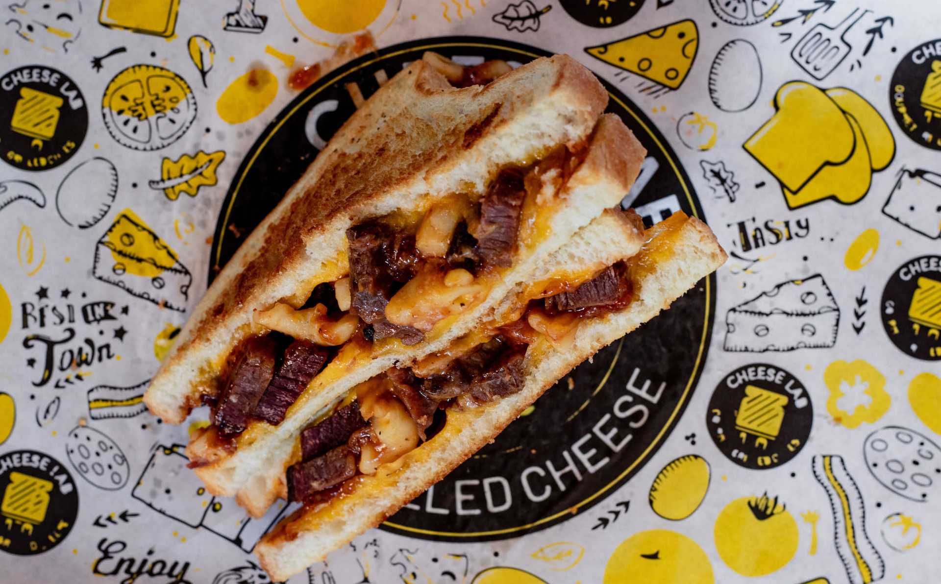 Grilled cheese sandwich with bacon and cheese on decorated paper.