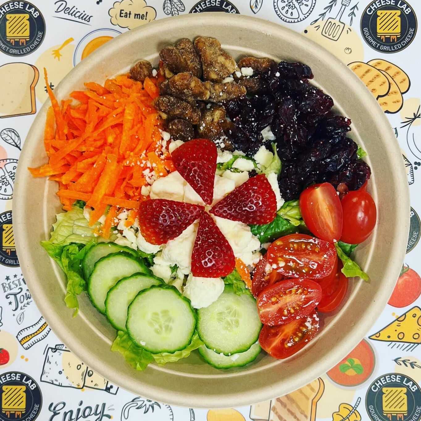 Healthy salad with fruits, vegetables, nuts, and cheese in a bowl.